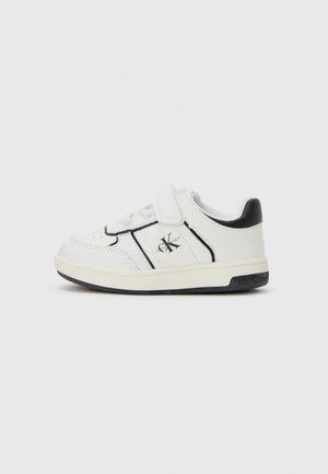 Baskets blanches pour tout-petits avec des accents noirs, bande Velcro, et logo Calvin Klein sur le côté et la semelle, sur fond blanc uni.