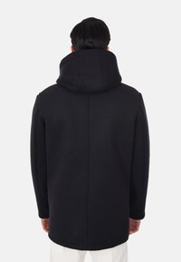 Cappotto nero con cappuccio dal design lineare, realizzato in un tessuto strutturato, privo di hardware o decorazioni visibili sul retro.