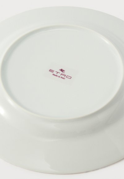 Assiette en céramique blanche retournée montrant le logo "ETRO Made in Italy" en rouge avec un petit cheval ailé au-dessus du texte.
