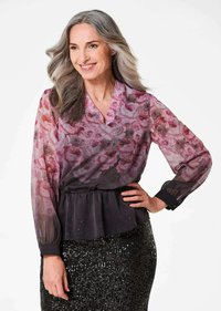 Durchsichtige Bluse mit Blumenmuster in Pink- und lila Farbtönen, mit einem Peplum-Taille; kombiniert mit einem schwarzen, paillettenbesetzten Rock mit tailliertem Schnitt.
