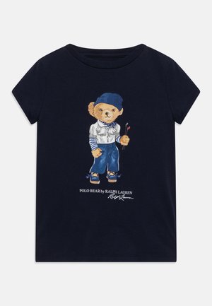 Námorně modré bavlněné tričko s podrobnou ilustrací medvěda v volnočasovém oblečení, který drží golfové hole, a s nápisem "Polo Bear by Ralph Lauren" pod obrázkem.