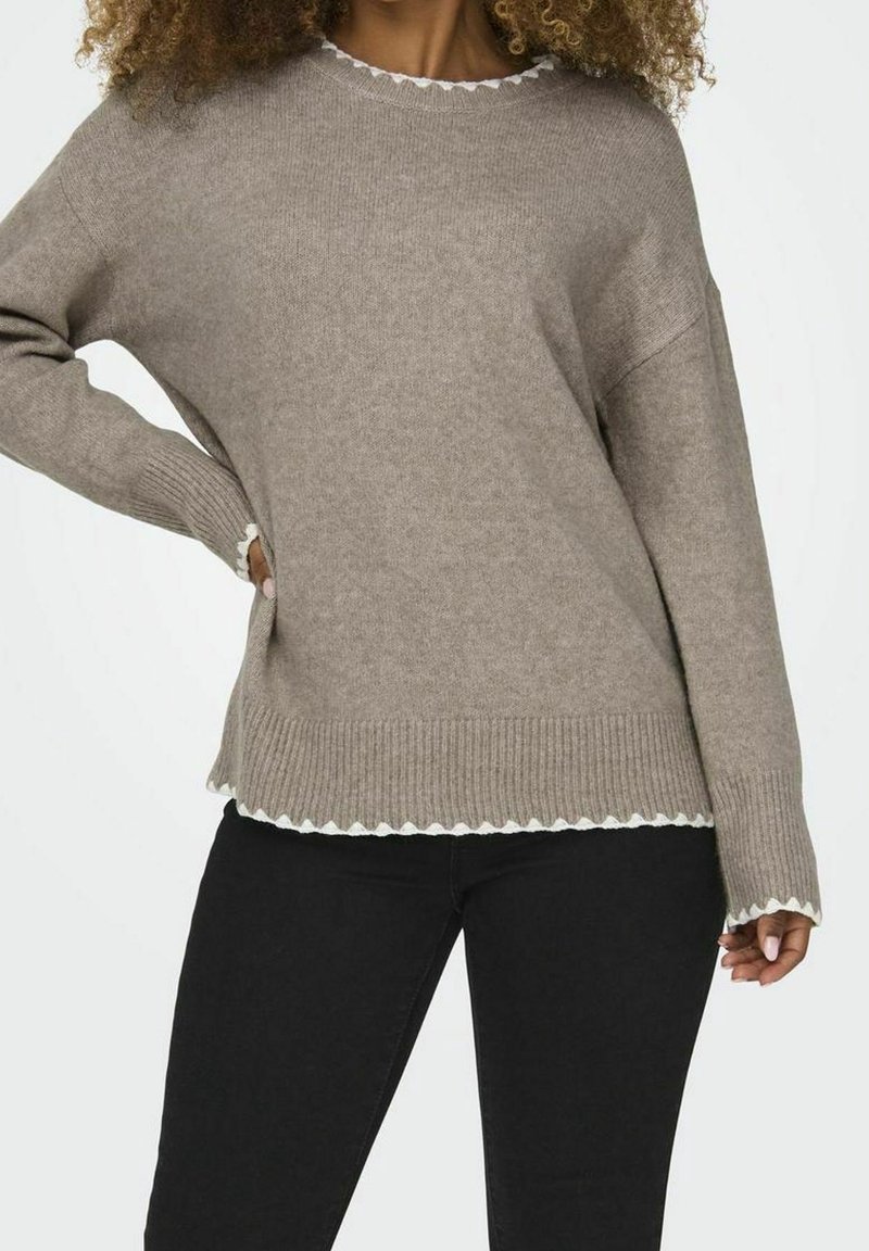 Hellbraunes gestricktes Sweatshirt mit geripptem Bund und Saum, verziert mit einer gewellten weißen Kante entlang des Ausschnitts und des unteren Saums. Lange Ärmel.