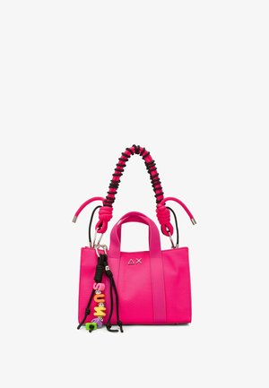 Sac à main rose vif avec poignée tressée noire et rose, ferrures argentées, et breloque colorée formant le mot "SUM" suspendue sur le côté avant.