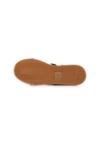 La suola della sneaker presenta un motivo a spina di pesce, realizzata in un materiale di gomma marrone texturizzato. Il logo è visibile al centro.