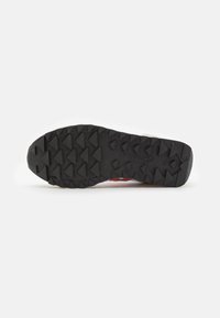 Suola di sneaker in gomma nera con un motivo di battistrada triangolare, bordo superiore di colore chiaro a contrasto, con dettagli di branding lungo il lato.