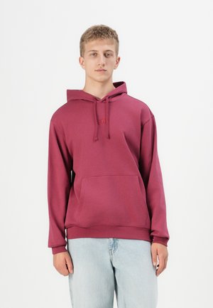 Maroon hooded sweatshirt with a front pocket, featuring a plain design and ribbed cuffs. Paired with light blue denim jeans.