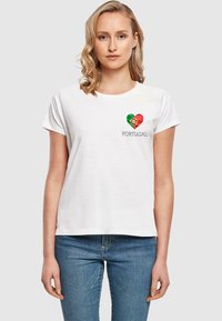 Hvit bomull t-skjorte med et hjerteformet design med det portugisiske flagget og ordet "PORTUGAL" i grått under. Korte ermer.