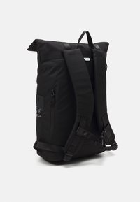 Sac à dos noir au design roll-top, avec des bretelles rembourrées, une poche zippée à l'avant et un minimalisme dans le branding. Fabriqué à partir d'un tissu durable et texturé.