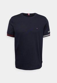 Tmavě modré bavlněné tričko s kulatým výstřihem, krátkými rukávy, kontrastními červenobílými pruhovanými prvky a malým logem na hrudi.