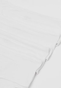 Mutande di cotone bianche con elastico in vita, caratterizzate da una texture a coste e una superficie liscia, presentate impilate in un'ordinata disposizione piegata.