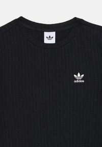 Juodas juostuotas marškinėliai su apvalia iškirpte, su baltu Adidas logotipu kairėje krūtinės pusėje. Minkšta tekstūra ir prigludusi forma.