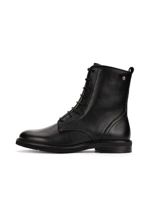 Botín de cuero negro con cordones en la parte delantera, puntera redonda, tacón bajo y un pequeño logo metálico cerca de la parte superior en el lateral exterior.