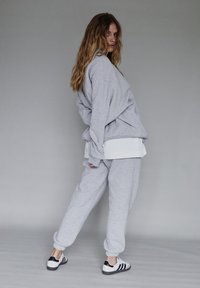 Jasnoszara, oversize'owa bluza i pasujące dresy, z żeberkowymi mankietami. Uzupełnione białymi i czarnymi sneakersami w paski.