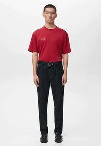 Tricou roșu din bumbac cu decolteu rotund și mâneci scurte, asortat cu pantaloni din denim închis, cu talie înaltă, și pantofi negri cu șireturi.