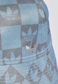 Pălărie de tip bucket, cu un model albastru, confecționată dintr-un material texturat, având un logo proeminent în formă de floare gri și un design în carouri.