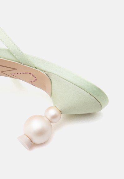 Πράσινο ανοιχτό παπούτσι με λουρί και μοναδικό τακούνι αποτελούμενο από δύο σφαίρες που μοιάζουν με μαργαριτάρια, φωτογραφημένο σε λευκό φόντο.