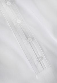 White shirt featuring a placket with five white buttons, neat stitching, and smooth fabric texture. Simple and clean design.