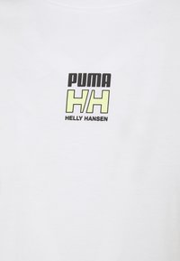 Balta kokvilnas t-krekls ar melnu un limonzaļu grafisku logo, kurā ir teksts "PUMA" un "HH". Klasisks apaļais kakla izgriezums.