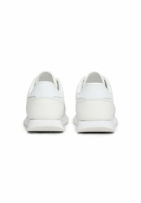 Zapatillas deportivas blancas con un talón texturizado, parte superior lisa y un perfil bajo. Cuentan con una suela de goma sólida para mayor tracción.