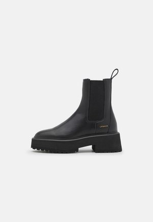 Schwarzer Leder-Chelsea-Stiefel mit klobiger Sohle, elastischen Seitenteilen, Zuglasche an der Ferse und kleinem goldfarbenem Markenaufdruck an der Außenseite.