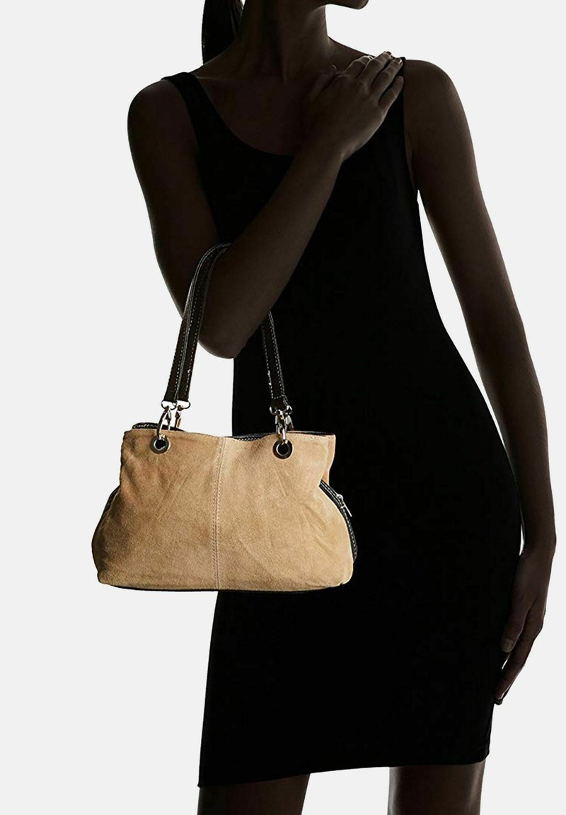 Borsa in suede beige con due manici in pelle nera, dotata di hardware in argento e dettagli con zip ai lati. Texture liscia, forma morbida.