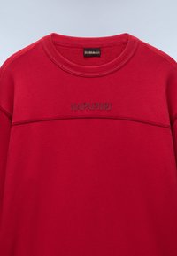 Κόκκινο φούτερ από μαλακό ύφασμα. Διαθέτει στρογγυλή λαιμόκοψη και υφασμάτινο λογότυπο «NAPAPIJRI» στο ίδιο χρώμα στο ύψος του στήθους.