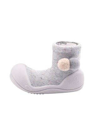 Zapato calcetín para bebé en gris claro con suela y puntera de goma, decorado con dos pompones en beige y gris en el tobillo.