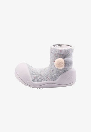 Zapato calcetín para bebé en gris claro con suela y puntera de goma, decorado con dos pompones en beige y gris en el tobillo.