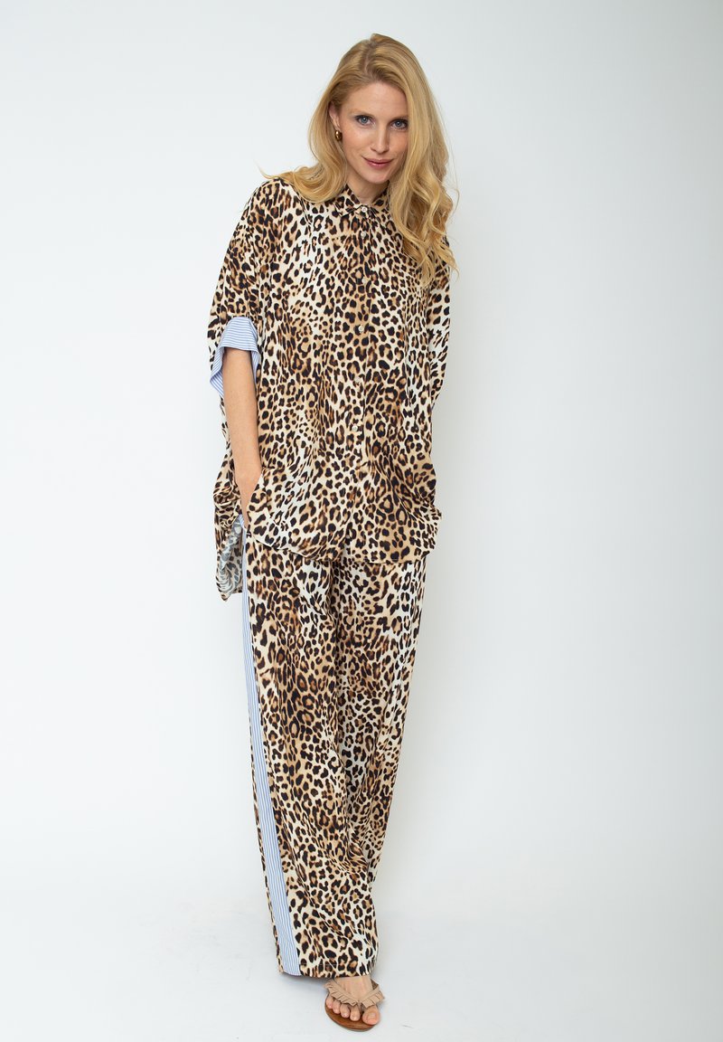 Koszula w panterkę w oversize'owym kroju z pasującymi spodniami z szerokimi nogawkami, z subtelnymi niebieskimi paskami na rękawach i bokach. Gładka tekstura materiału.