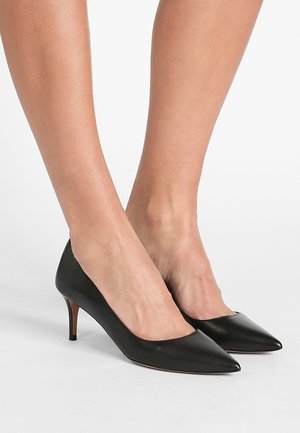 Czarne skórzane czółenka na wysokim obcasie ze szpiczastym noskiem, cienkim obcasem typu szpilka, gładką fakturą i minimalistycznym wzornictwem.