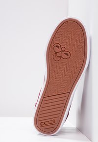Tenisii roșii au o talpă din cauciuc texturat, cu un model în dungi de pește și un logo embosat. Talpa intermediară albă completează designul.
