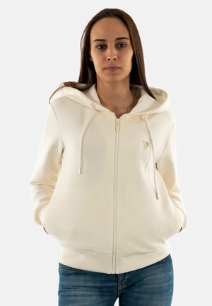 Felpa con zip color crema, texture liscia, con cordini regolabili e un discreto logo sul petto. Design aderente con tasche.