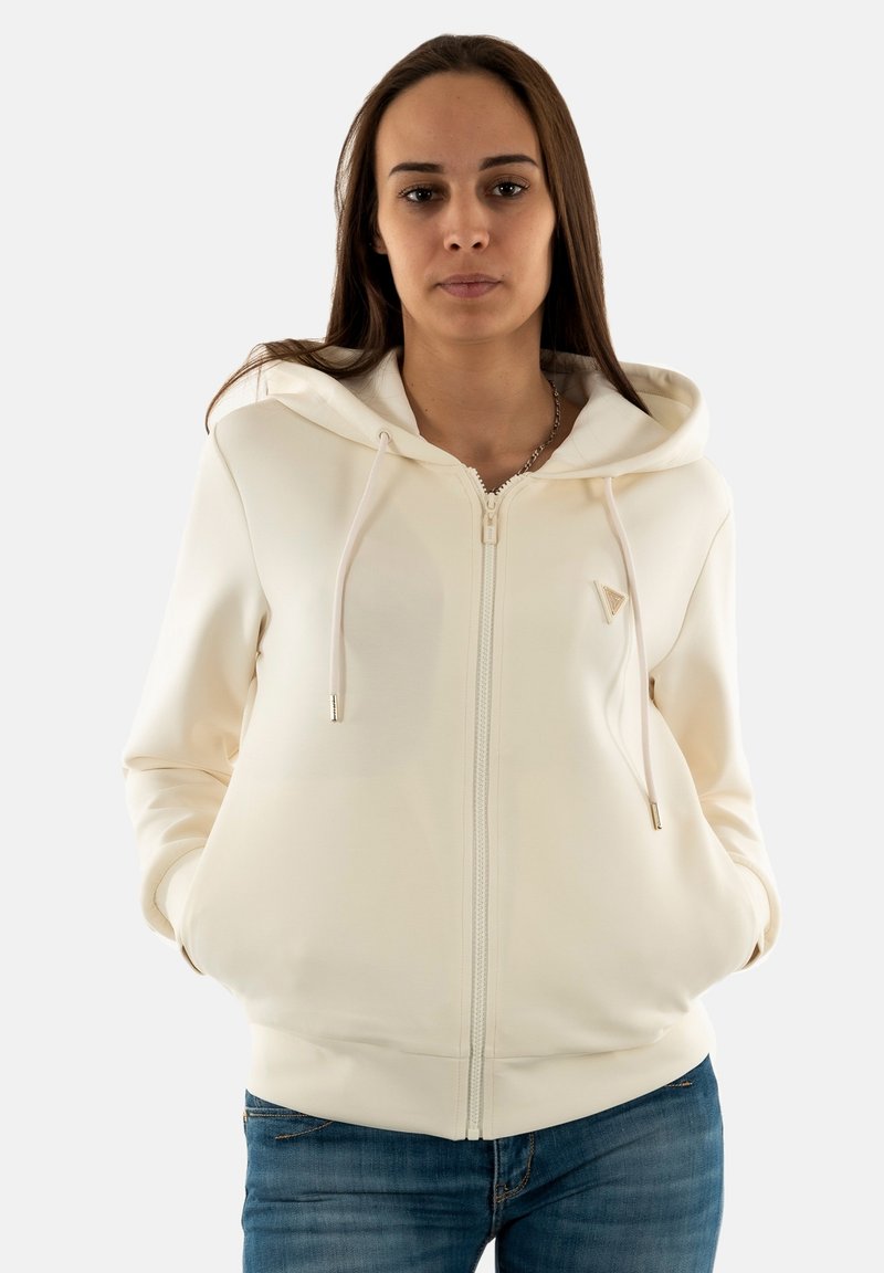 Felpa con zip color crema, texture liscia, con cordini regolabili e un discreto logo sul petto. Design aderente con tasche.