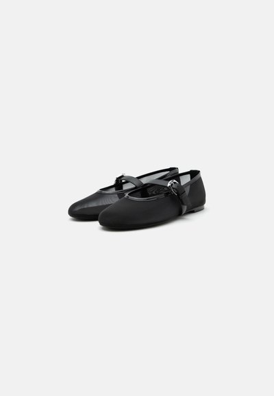 Paire de ballerines Mary Jane noires avec bouts arrondis et brides à boucle sur fond gris clair.