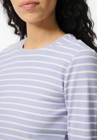 Top de color morado claro con relieve que presenta franjas horizontales blancas, con un escote redondo y una textura que resalta un diseño ajustado.