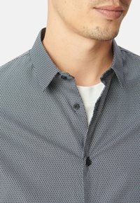 Camicia a maniche corte con un motivo geometrico in blu navy e bianco, caratterizzata da un colletto button-down e bottoni neri sul davanti.