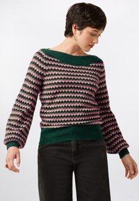 Knitted sweater with a geometric pattern in pink, green, and cream. Features a wide green neckline and ribbed cuffs and hem.