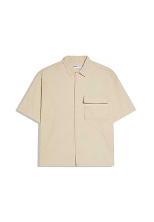 Cămașă bej cu mâneci scurte, cu nasturi, guler și un buzunar mare în față, cu clapetă, pe partea stângă.