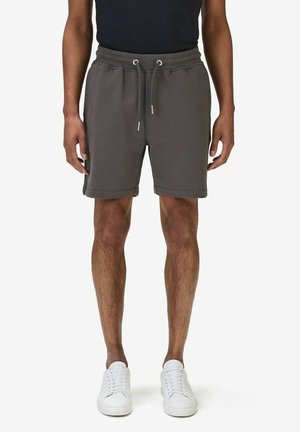 Grå bomulds shorts med elastisk talje og snor, med sidelommer og lige ben. Båret med hvide sneakers.