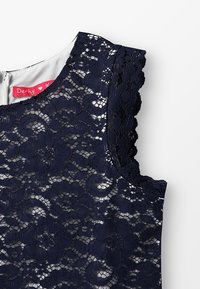 Námořnické krajkové šaty s květinovým vzorem, vlnitými okraji a podšívkou. Zapínání na zip na zadní straně s visačkou s nápisem "Derhy."