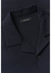 Camicia navy con texture e colletto, caratterizzata da un bottone e un'etichetta tessuta con la scritta "Matinique". Tessuto morbido e traspirante.