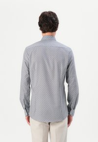 Patterned button-up shirt in lightweight fabric, featuring a blue, white, and red geometric design, spread collar, and long sleeves.