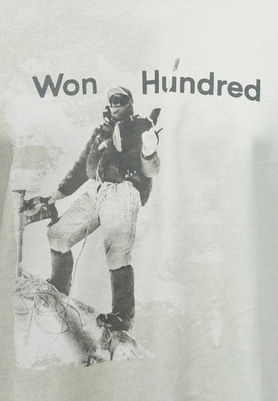 Γκρίζο T-shirt με εκτύπωση σε ασπρόμαυρο ενός αναρριχητή με εξοπλισμό που κρατάει ένα τσεκούρι. Το κείμενο αναγράφει "Won Hundred" πάνω από την εικόνα.