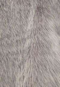 Grå fuskpäls med en mjuk, texturerad yta, som har varierande längder på fibrerna som skapar en naturlig, vågig look.