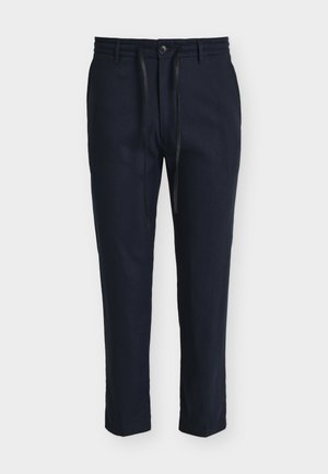 Marineblå herre skreddersydde bukser med beltestropper, frontknapp, glidelås og svart snor på hvit bakgrunn.