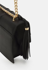 Borsa a tracolla in finta pelle nera con tracolla a catena dorata, forma rettangolare e dettaglio con nappe laterali. Texture liscia e design minimalista.