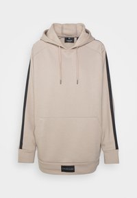 Sweat à capuche beige avec des bandes noires sur le côté, poche kangourou, capuche avec cordon de serrage et poignets côtelés. Présente une étiquette logo Calvin Klein sur l'ourlet.
