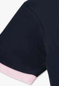 Manche courte d'une chemise tricotée bleu marine avec un poignet côtelé rose clair sur fond blanc.