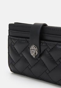 Czarny skórzany portfel z pikowanym wzorem, posiadający srebrny dekoracyjny zamek oraz gładką teksturę. Kompaktowy kształt z przegrodami na karty.