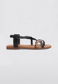 Sandalía negra con múltiples correas, con un acento de estampado de leopardo y suela marrón. Hebilla ajustable en la correa del tobillo. Diseño plano.